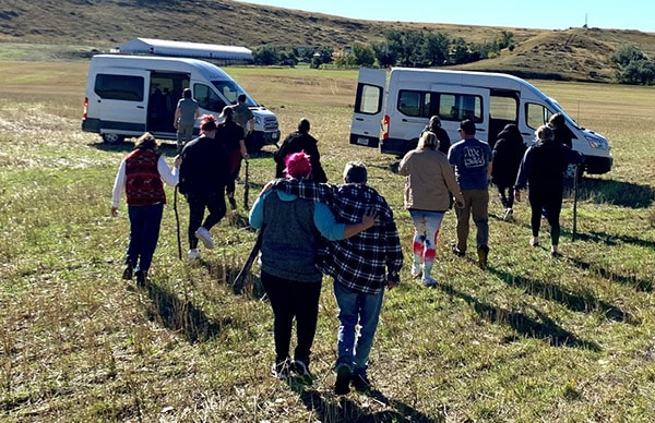 A group of people walking through a field towards some vehicles