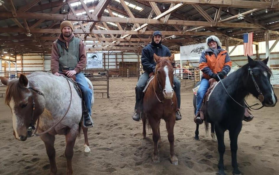 3 People sitting on horses smiling for the camera